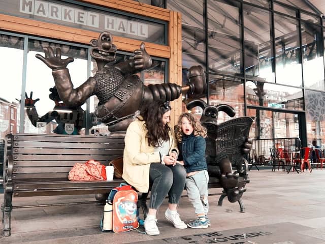 Mother and child sit on the Wallace and Gromit bench outside Preston Markets