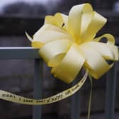 A yellow ribbon with a message of hope written on it is tied to a bridge over the River Wyre in St Michael's