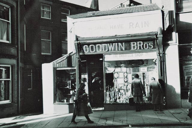 Goodwin Bros umbrella shop, Orchard Street, Preston, taken around 1975. It's hard to make out in this image, but above the main shop sign is the saying 'We Shall Have Rain' - a line taken from old weather folklore: If it rains on St. Swithin's Day [15 July] then we shall have rain for forty days
