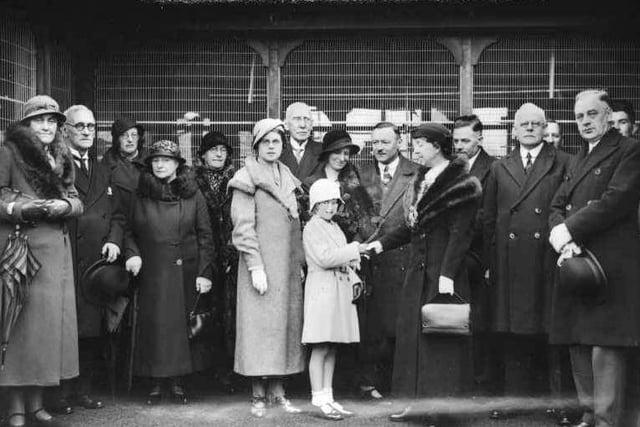 This picture shows the opening of Haslam Park Aviary in 1934. The aviary was presented to the town by Councillor John J. Ward. Here the Mayor of Preston, Mrs. AV Pimblett, accepts the aviary from Miss Peggy Ward on behalf of the children of Preston. The aviary was a delightful building having an overall thatched roof. It was situated behind the Park keepers house near the east gate