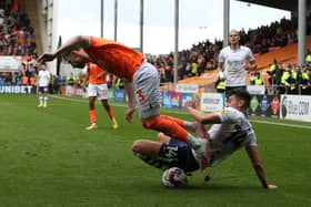 Blackpool's James Husband is tackled by Preston North End's Jordan Storey.