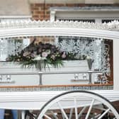 A white horse drawn carriage with Isabelle's coffin adorned with pink and white flowers makes its way to St Teresa's Church