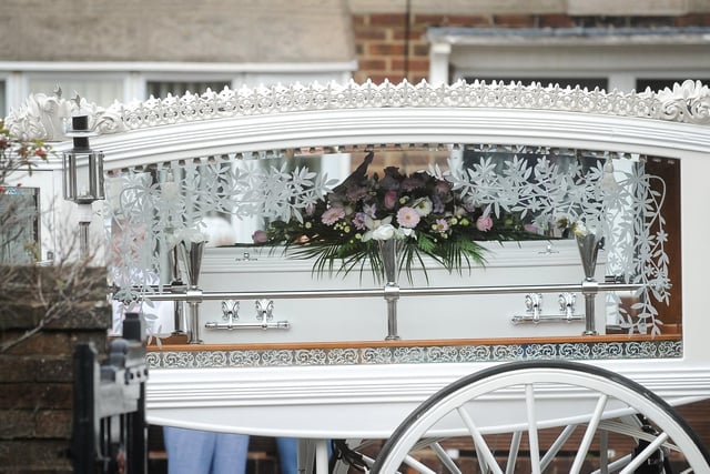 A white horse drawn carriage with Isabelle's coffin adorned with pink and white flowers makes its way to St Teresa's Church