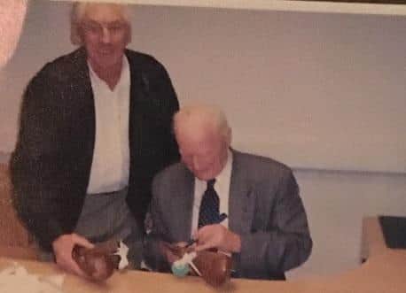 Malcolm watches Sir Tom sign the boots at Deepdale in 2006.