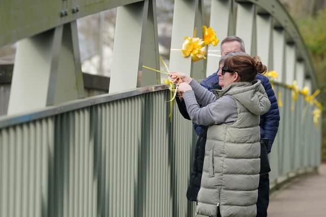 Nicola Bulley's sister, Louise Cunnigha, with her mother and father-in-law, ties a yellow ribbon to a bridge over the River Wyre in St Michael's on Wyre (Credit: Peter Byrne/PA Wire)