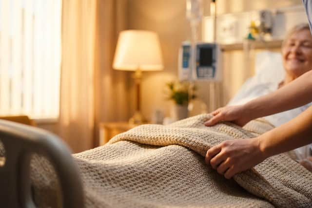 Carer helps elderly patient into bed