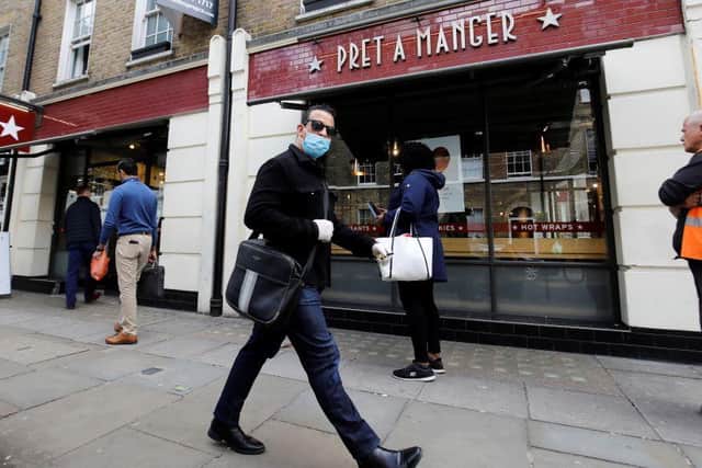 A man wearing PPE (personal protective equipment) passes customers queuing to enter a recently re-opened Pret-A-Manger shop which had originally closed-down due to the COVID-19 pandemic in London (Photo: TOLGA AKMEN/AFP via Getty Images)