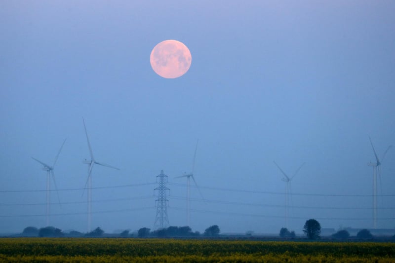 The full moon sets over Little Cheyne Court Wind Farm on the Romney Marsh in Kent (PA)