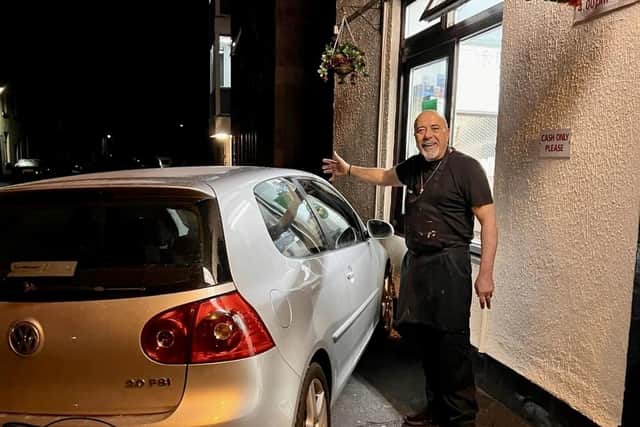Manager of Brown's Fish and Chip shop in Chorley Georgio Barnaba poses next to a car which had plunged into the side of the wall after the owner forgot to pull the handbrake up before leaving the vehicle