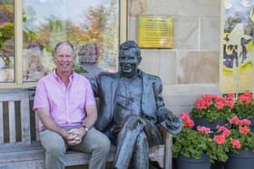 Guy sitting with the statue of his late father that's situated at the front of the garden centre