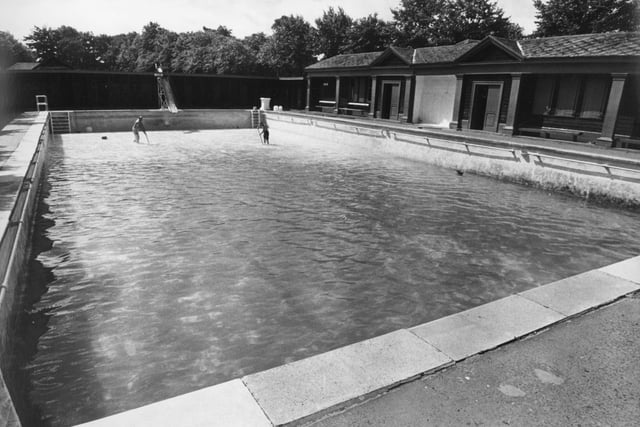 Mr Thomas Walton, and Mr Albert Atkinson, pool supervisor, sweeping the algae off the floor of Haslam Park baths