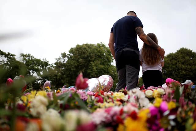 Members of the public lay and look at floral tribute left outside the Town Hall in Southport.