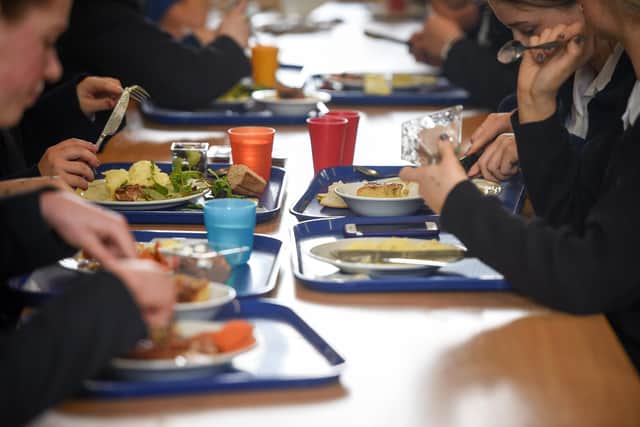 Students eat their school dinner from trays and plates during lunch