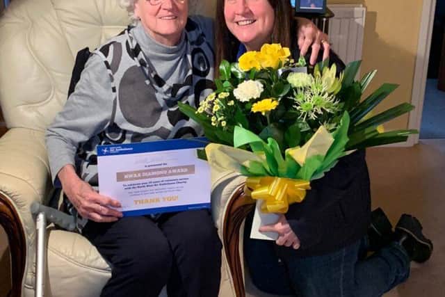 Violet Leach is presented with a certificate and flowers by volunteer coordinator Lisa Rawcliffe