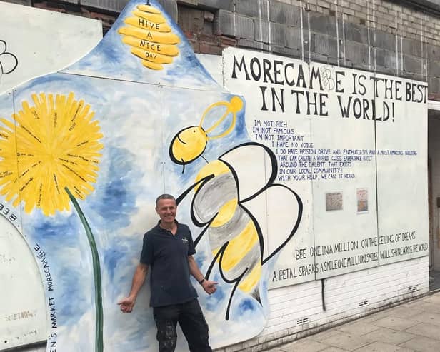 Nick Smith with the bee mural on the front of the Queen's Market in Victoria Street.