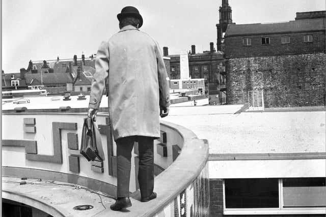 Don't look down... the mystery man gingerly makes his way along the narrow wall which topped St George's Shopping Centre in the 1960s