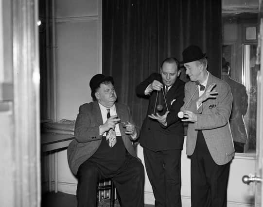 Stan Laurel and Oliver Hardy playing with yo-yos backstage at the Empire Theatre in 1954.