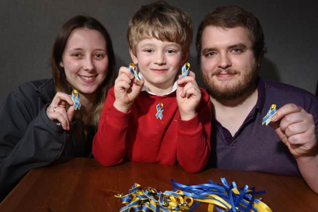 LANCASHIRE POST - 23-03-22 
Jonathan pictured with parents Adele Brindle and James Wright, who help him make the ribbons.