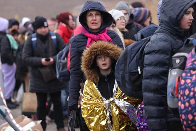 MEDYKA, POLAND - MARCH 07: People, mostly women and children, who had just arrived from war-torn Ukraine wait for buses on a freezing day at the Medyka border crossing on March 07, 2022 in Medyka, Poland. Over one million people have arrived from Ukraine since the Russian invasion of February 24, and while many are now living with relatives who live and work in Poland, others are journeying onward to other countries in Europe.  (Photo by Sean Gallup/Getty Images)