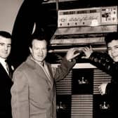 A young Cliff Richard pictured with guitarist, Burt Weedon and jukebox sales manager, Mike Town. Photo courtesy of Paul Walker and ditchburn.co.uk.