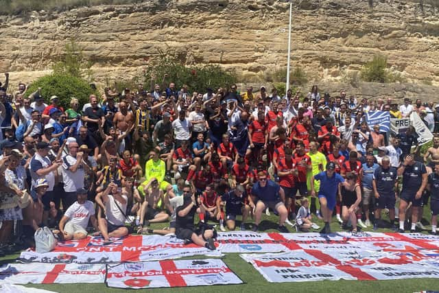 Supporters who travelled to the game join the players and staff for a picture after the game.