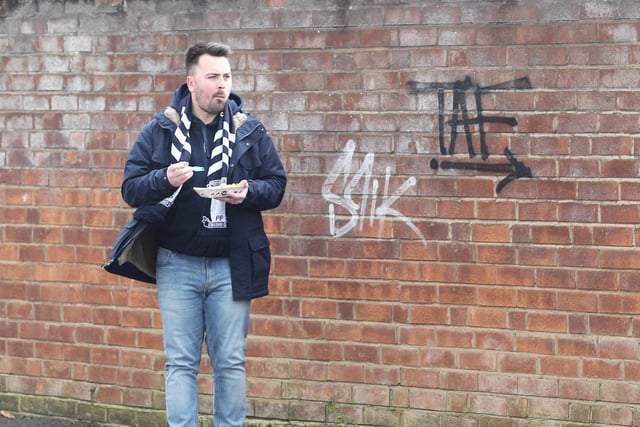 A North End supporter enjoys a bit to eat outside the Alan Kelly Town End