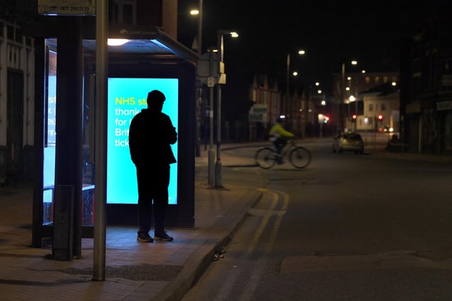 One lone traveller waiting at the bus stop, with a thank you NHS billboard behind him. The 'thank you NHS' slogan became the norm on billboards across the country