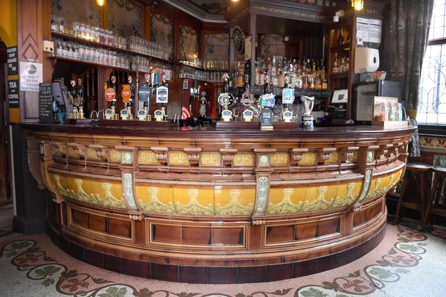 The man bar area featuring a glazed tiled bar, mosaic floor tiles featuring hop and grape designs