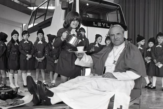 Pope John Paul II (alias Bill Bird the Liverpool policeman) puts his feet up while Sarah Moss of Leyland Brownies pours the tea. The surprise was part of a national challenge in which thousands of brownies arranged the most unusual tea-party. The Leyland Brownies chose to stage theirs in the world famous Popemobile