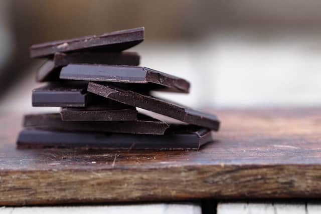 Stack of broken dark chocolate bar pieces on a wooden background. Horizontal