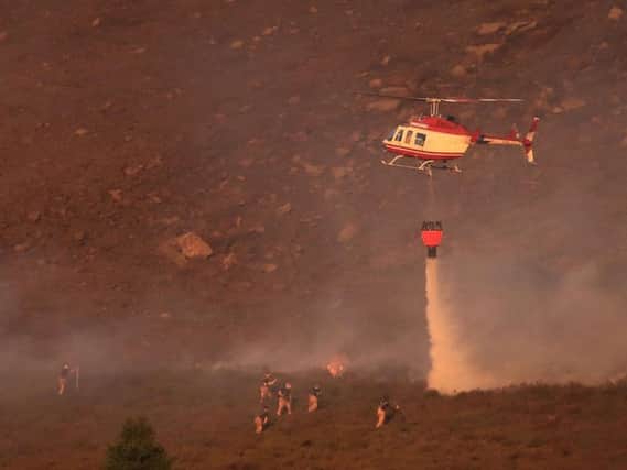 A helicopter helps fire crews on Saddleworth Moor this evening