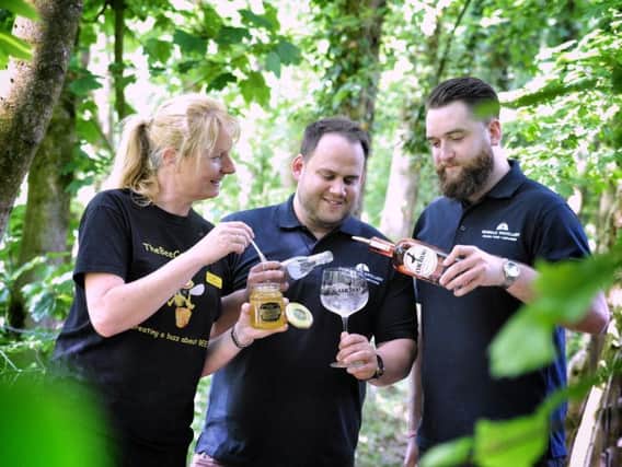 Kath Cordingley of The Bee Centre helps Mark Long and Tom Fitzpatrick of Cuckoo Sunshine Gin, which is made using the centre's honey.