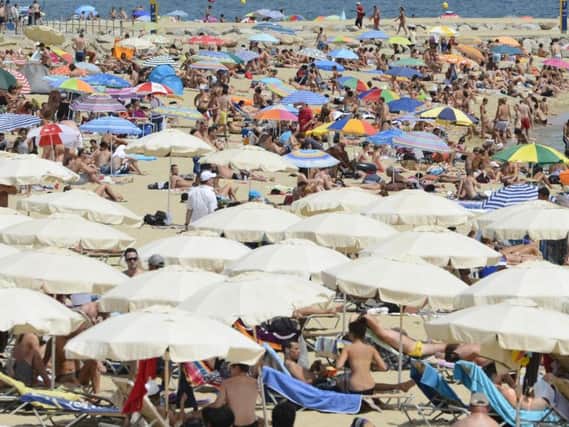 People enjoy the sun at Barceloneta Beach in Barcelona, Spain