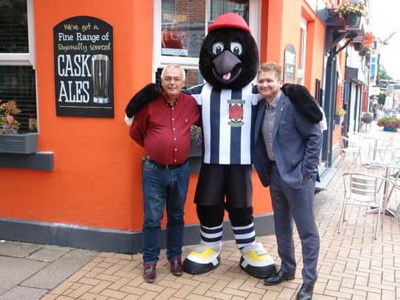 Chorley FCs Josh Vosper (left) and The Crowns owner Frank Smalley celebrate the new club-inspired walls with Chorley FC mascot Victor Magpie at The Crown, known for its eye-catching orange exterior