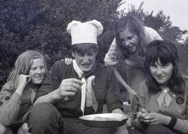 Charnock Richard patrol leader Frank Wilson gives his opinion of the cooking of 3rd Leyland Guides (from left) Jacqueline Rhodes, Susan Weedall, and Patricia Walmsley, at a cooking competition between scouts and guides from the Chorley and Leyland areas, as they faced each other during a "cook-off" in Worden Park, Leyland