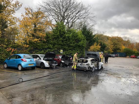 Firefighters dampen down flames after three cars burst into flames