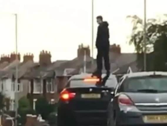 A youth stands on the roof of a BMW in Blackpool Road, Ashton during a confrontation between two groups which halted traffic.