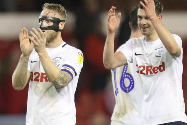 A masked Tom Clarke and Paul Huntington applaud the Preston fans at the final whistle