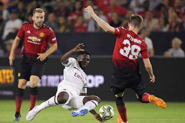 AC Milan midfielder Franck Kessie, center, tries to kick past Manchester United midfielder Scott McTominay