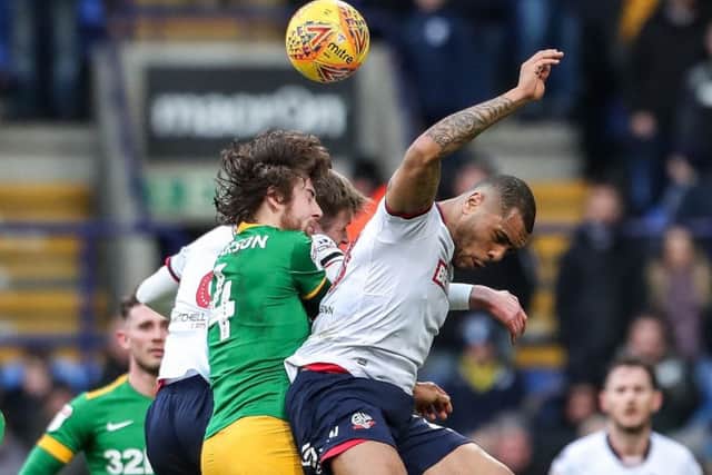 Preston midfielder challenges Bolton striker Josh Magennis in the air
