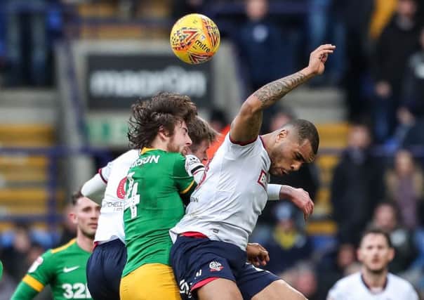 Preston midfielder challenges Bolton striker Josh Magennis in the air