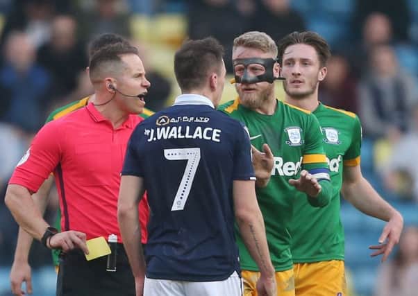 Referee Stephen Martin prepares to book Millwall midfielder Jed Wallace