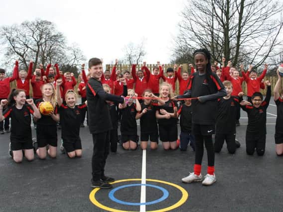 Year six pupils Max and Eniola cutting the ribbon to officially open the MUGA along with other members of the schools Sports Council.
