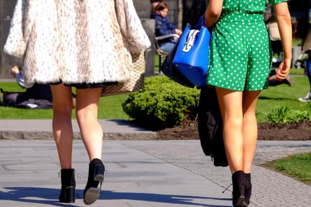 Two women wearing short skirts walk in the sunshine as upskirting, the invasive practice of taking an image or video up somebody's clothing, becomes a specific criminal offence in England and Wales, punishable by up to two years in custody.