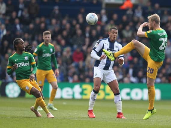 Preston striker Jayden Stockley battles for a high ball against West Bromwich Albion, watched by Daniel Johnson