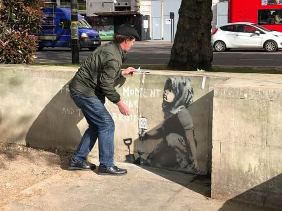 Calvin Benson, 48, puts a protective plastic sheeting over an artwork which appears to be by street artist Banksy. The environmental artwork has appeared near the Extinction Rebellion camp in Marble Arch, London.