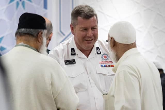 A member of the fire service speaks with worshippers at the Quwwatul Islam Mosque. Photo: Kelvin Stuttard