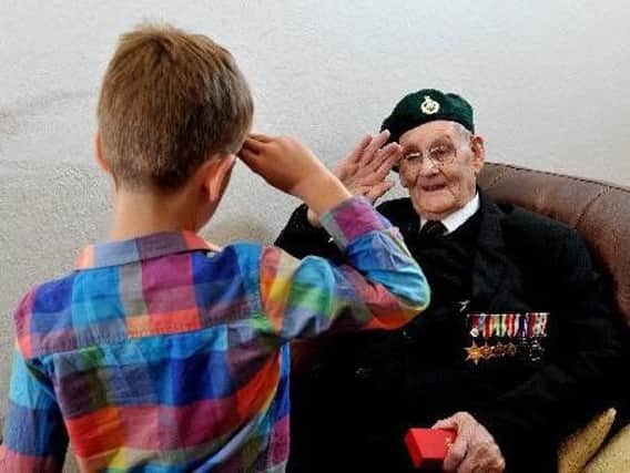 John Dowling worked as a signaller receiving messages on D-Day and is                                                                         pictured here teaching his great grandson Leo Blessley to salute.