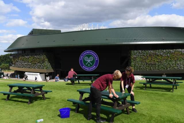 Members of staff prepare the benches outside court 1 (Photo by Shaun Botterill/Getty Images)