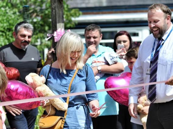 Lisa Roussos cuts the pink ribbon to the memorial garden for Saffie as headteacher of Tarleton Communicy Primary School, Chris Upton helps out and her husband, Andrew looks on